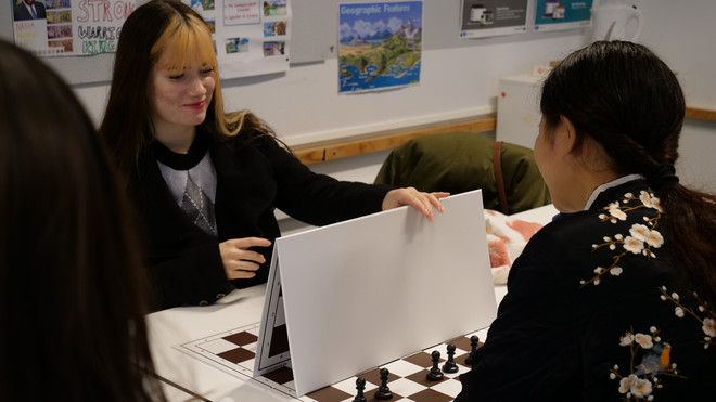 To piger spiller skak med en plade mellem sig.